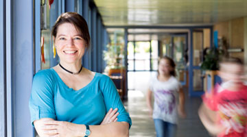 Smiling educator standing in hall as students walk past