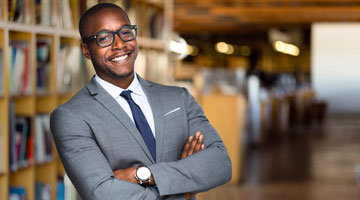 Confident smiling educator standing in library