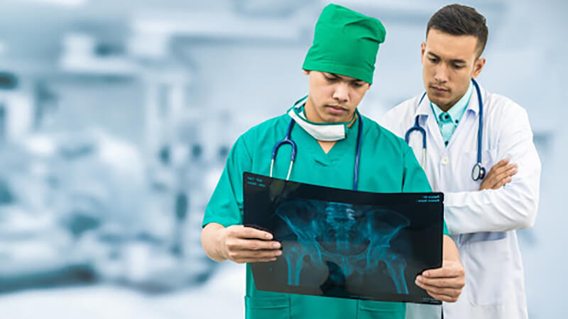 A surgeon and a doctor look at patient x-rays together.