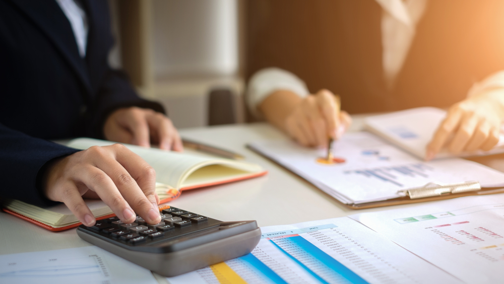 A forensic accountant reviews paperwork on an office desk.