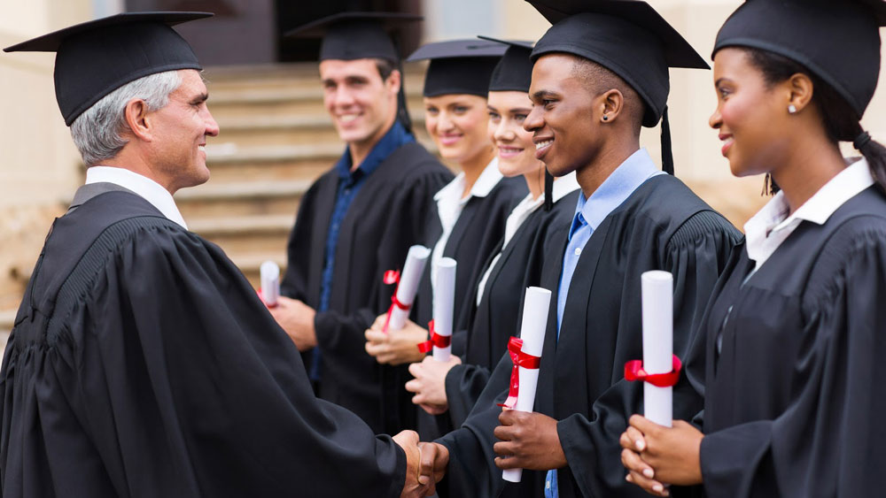 College dean awarding diplomas to graduates.