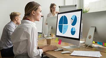 Woman  at desk analyzing data on computer