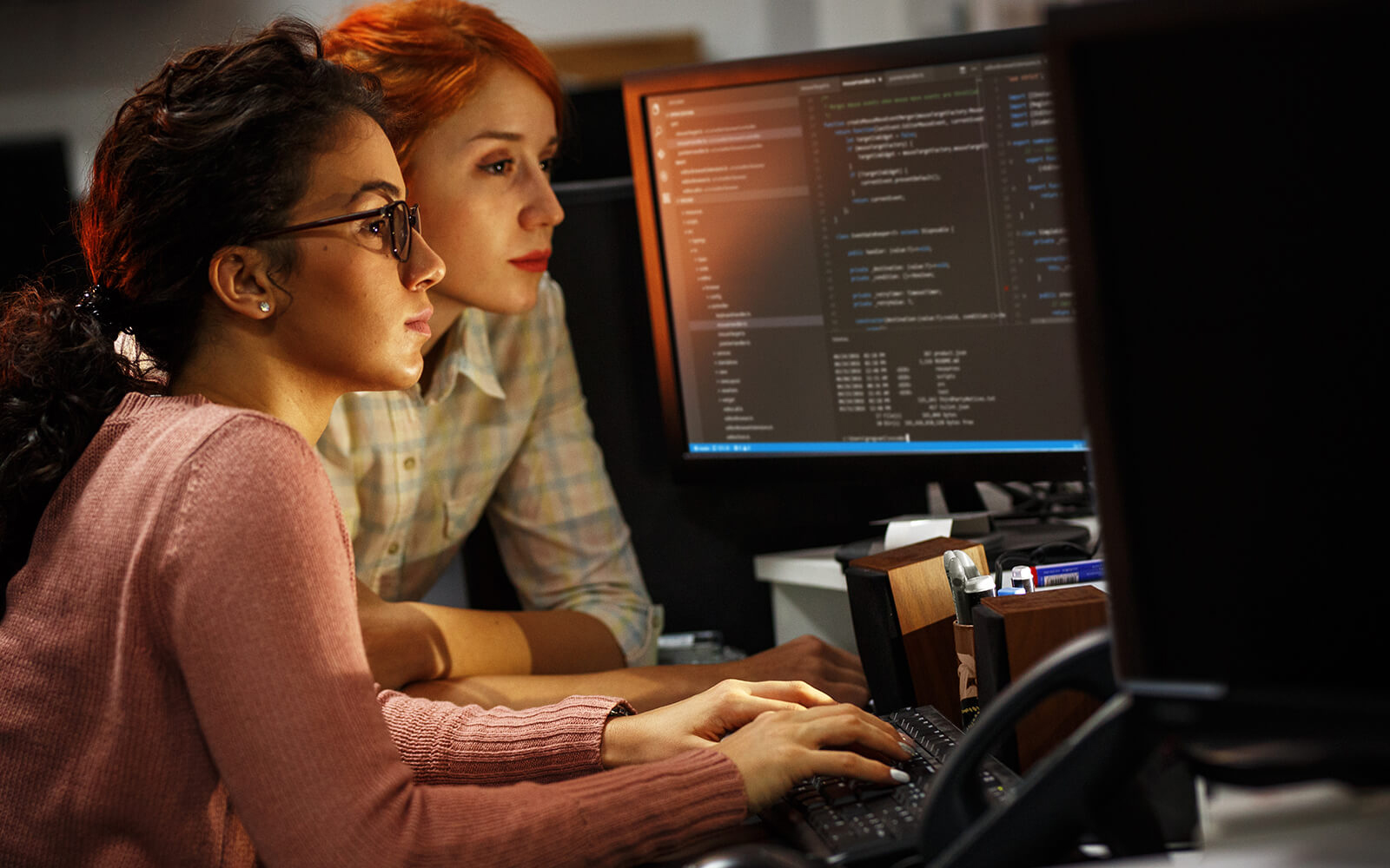 Two DevOps personnel working on computer