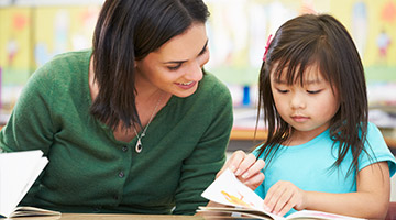 Teacher going through a book with a little girl