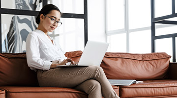 Woman sitting on a couch looking at her laptop