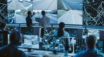 A control room with people monitoring surveillance screens.