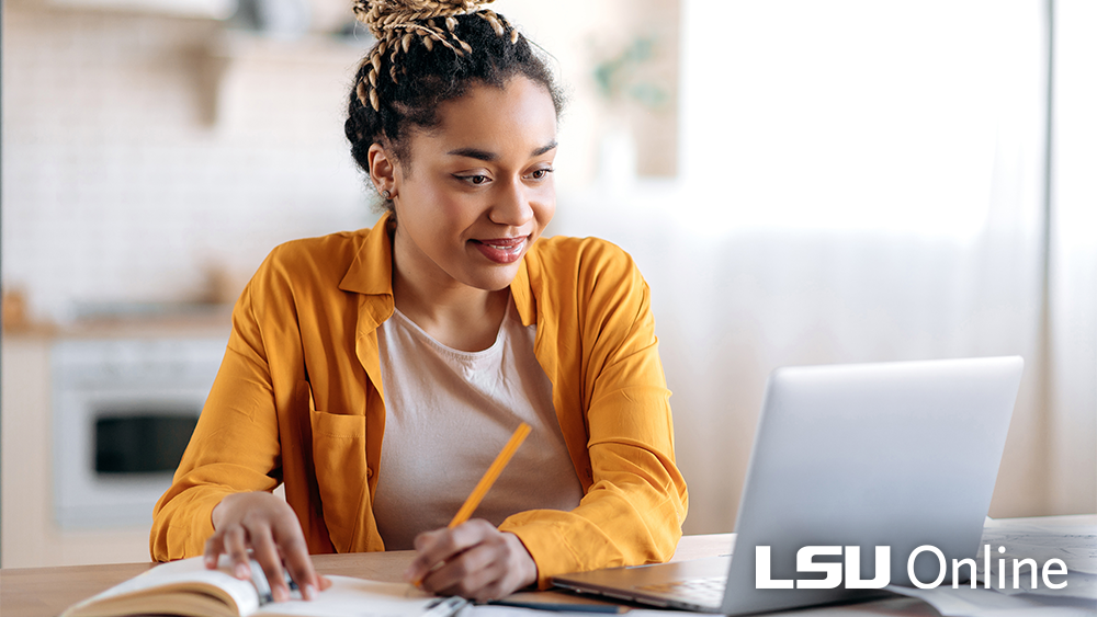 Woman writing and working on laptop
