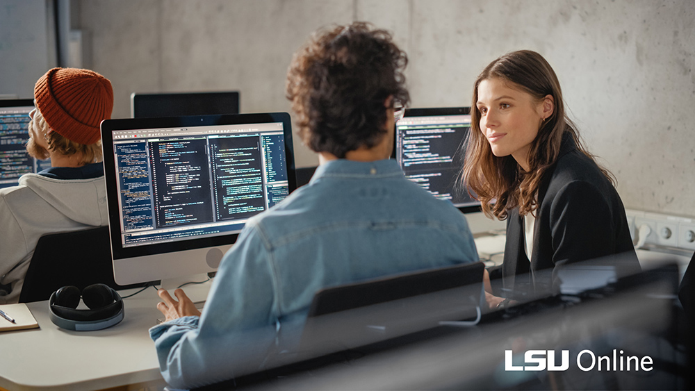 two people talking in front of computer screens