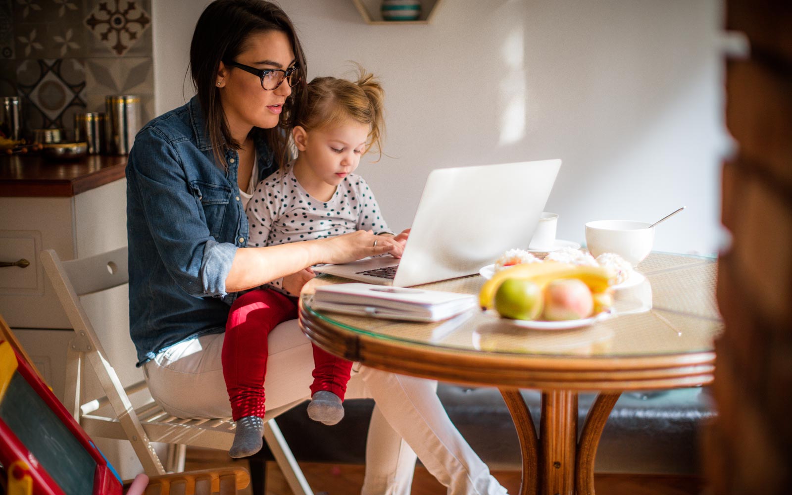 Young mother and child in kitchen studying online